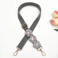 Detail of grey canvas strap featuring handmade crochet flowers and gold metal hardware - Gray
