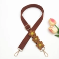 Detail of handcrafted crochet daisy flowers on a brown woven bag strap with gold lobster clasps - Brown