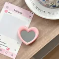 Detailopname van de roze hartvormige spiegeltelefoonhouder op een houten tafeloppervlak - Roze