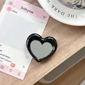 Detailopname van de hartvormige zwarte telefoonspiegelhouder op een stijlvolle tafel - Zwart