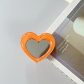 Dettaglio di un supporto per telefono a cuore arancione con specchio su una rivista - Arancione