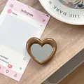 Bruine hartvormige telefoonhouder met spiegel op een houten bureau-omgeving - Karamel