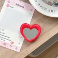 Detail van een rode hartvormige inklapbare telefoonspiegel op een houten bureau - Rozerood