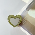 Macro detail of heart-shaped sage green marble phone mirror stand on lifestyle magazine - Dark Green