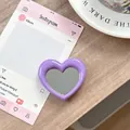 Detailopname van de paarse hartvormige spiegeltelefoonhouder op houten tafel - Donkerpaars