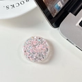 Close-up of a round pink glitter phone socket grip with sparkling sequins on a white desk - Glue Grip - Starry Sequins - Pink