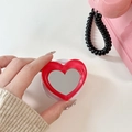 Close-up of heart-shaped red mirror phone socket held in hand with retro aesthetic - Rose Red
