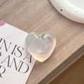Vista ravvicinata del supporto per telefono a forma di cuore iridescente su legno - Cuore Opaco Adesivo - Luce Blu