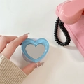 Blue heart-shaped mirror phone socket held by hand with a retro pink phone background - Light Blue