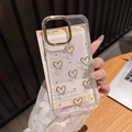 Primer plano de funda iPhone con corazones dorados y anillo protector de cámara - Círculo Dorado-Pegamento de Gota de Purpurina-Corazón Hueco de Perla Dorada / iPhone 17 Pro Max