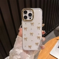Detalle de funda brillante con lazos dorados y marco de protección para lente de cámara - Círculo Dorado-Pegamento de Gota de Purpurina-Lazo de Perla Dorada / iPhone 17 Pro Max