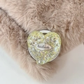 Dettaglio di un supporto per telefono a cuore glitterato con etichetta su sfondo morbido - Stile Cuore Magnetico / Giallo