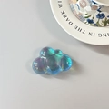 Detailed view of iridescent cloud phone grip with vibrant holographic finish on desk - Adhesive Cloud / Blue