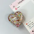 Macro detail of a heart-shaped resin phone grip with glitter and handmade metal plate - Style 4