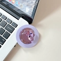 Detail of a purple gemstone cell phone grip holder on a silver laptop surface - Purple
