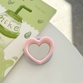 Detail of heart-shaped magnetic phone grip mirror in soft pink on a white desk - Pink