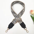 Close-up of geometric jacquard shoulder strap with gold metal lobster clasp and adjuster - Gold Buckle / Beige Black + Black Leather