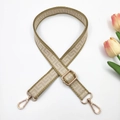 Detail view of woven adjustable bag strap with gold metal buckles and floral decor - Beige and Khaki Edge