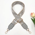 Close-up of geometric jacquard bag strap with grey leather ends and gold metal hooks - Beige Base Grey + Grey Leather