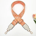 Close-up of geometric jacquard bag strap with grey leather ends and gold metal buckles - Beige Orange + White Leather