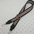 Close-up of adjustable woven shoulder strap with iconic red and green stripes and gold hooks - Black Red Green Stripe