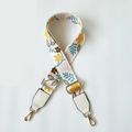 Close-up of floral patterned bag strap with golden metal snap hooks and buckles - White Floral + White