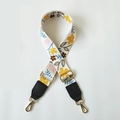 Macro view of wide woven bag strap with floral pattern and golden metal buckles - White Floral + Black