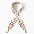 Close-up of ethnic embroidered bag strap with snowflake patterns and gold metal clips - White Floral Plant + Pink