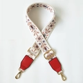 Close-up of ethnic embroidered bag strap with floral patterns and gold metal buckles - White Floral Plant + Bright Red