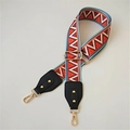 Close-up of ethnic style wide woven shoulder strap with red patterns and gold lobster clasps - Dazzling Black Leather