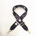 Close-up of ethnic floral strap with gold metal buckles and black leather ends - Black Floral Plant + Black