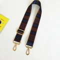 Detail of wide plaid canvas shoulder strap with gold swivel hooks and metal buckle - Brown