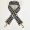 Detail of black and white woven bag strap featuring adjustable golden metal hardware - Black Strap Gold Buckle