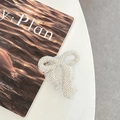 Detail of a sparkling bow-shaped phone grip with pave crystal rhinestones on white desk - Full Zirconia Bow / White / Adhesive