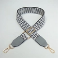 Close-up of black and white geometric woven strap with gold lobster clasps and grey leather - Gray Weaving with Gray Leather