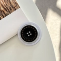 Gros plan d'un support de téléphone en forme de bouton noir avec des détails de couture - Modèle Magnétique / Noir