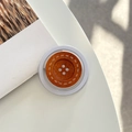 Détail du support de téléphone en bouton de bois sur un bureau blanc minimaliste - Modèle Magnétique / Café Orange