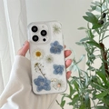 Detail showing real pressed blue flowers and white daisies on a glitter iPhone case - Dreamy Blue (Real Flower) / iPhone 17 Pro Max