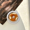 Detailaufnahme der Handyhalterung in Donut-Form mit Mandelstücken auf weißem Schreibtisch - Laugenbrezel - Donut / Magnetisches Modell