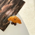 Nahaufnahme einer 3D Brezel Handyhalterung mit minimalistischem Smiley-Gesicht Design - Brezel-Croissant / Transparenter Klebetyp