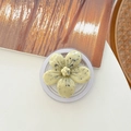 Detail view of flower-shaped phone grip with marble spots on a white and wood surface - Magnetic Ink-wash Cherry Blossom - Light Yellow