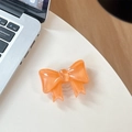Dettaglio dell'impugnatura per telefono a fiocco arancione con finitura perlata su tavolo bianco - Supporto Grande con Fiocco / Arancio Cristallo