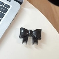 Dettaglio di un supporto per telefono a fiocco nero lucido con base trasparente a scomparsa - Supporto Grande con Fiocco / Nero Cristallo
