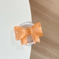 Macro detail of an orange glitter bow phone grip with MagSafe magnetic suction base - Orange
