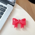 Detail of transparent rose red bowknot phone grip on a white surface next to a laptop - Large Bow Bracket / Crystal Rose Red