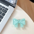 Detail of mint green glossy bow-shaped phone grip on a white desk with a laptop - Large Bow Bracket / Crystal Deep Green