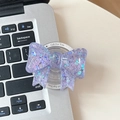 Macro detail of purple bow phone grip with colorful heart sequins on laptop keyboard - Purple
