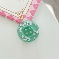 Macro detail of a green translucent resin button with cloud charms and four holes - Adhesive Large Button Cloud Pearlescent / Dark Green