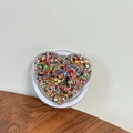 Close-up of heart-shaped phone grip filled with colorful sequins on white base - Magnetic Sequin Heart No. 5