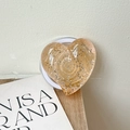 Close-up of heart-shaped amber glitter phone grip on a minimalist wooden surface - Large Crooked Heart - Dot Glitter - Magnetic / Transparent Orange